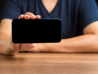 Wall Mural - hand holding a blank screen smartphone while sitting at the table