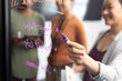 © Wavebreak Media - Creative businesswoman writing on glass wall in board room during meeting with colleagues