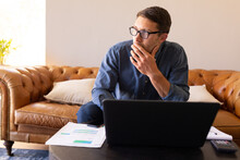 Thoughtful Caucasian Man Using Laptop And Calculating Finances At Home