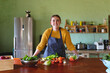 © Wavebreak Media - Portrait of smiling woman wearing apron leaning on kitchen counter with various fresh vegetables