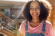 © Wavebreak Media - Portrait of happy biracial woman in bib overalls at home during sunny day