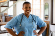 © Wavebreak Media - Portrait of smiling african american female doctor in scrubs standing with arms akimbo in hospital