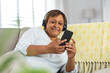 © Wavebreak Media - African american senior woman using smart phone and listening music through headphones at home