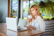 © APchanel - Young business woman working in a café shop on her break enjoying work from cup of coffee and laptop on table connecting work by internet network.