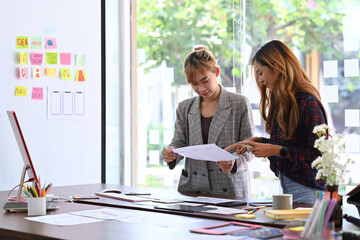 Wall Mural - two young women designer brainstorming and working on mobile app interface wireframe design together