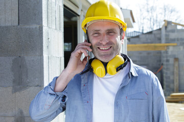 smiling builder talking on cell phone outdoors