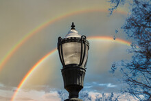 A Tall Black Lamp Post Surrounded By Bare Winter Trees With Blue Sky, Clouds And A Rainbow In The Sky In The Marietta Square In Marietta Georgia USA