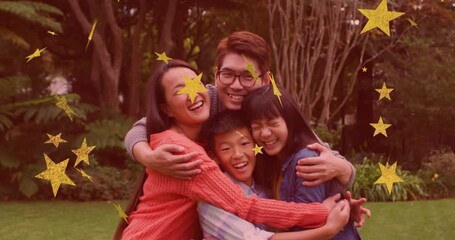 Sticker - Animation of gold stars over smiling asian parents, son and daughter embracing in garden