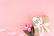 Mother's day background. Top view of gift box with pink bows - long ribbon and beautiful flowers on pastel pink background with copy space