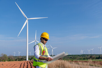 Wall Mural - Engineer wearing uniform ,helmet hold document inspection work in wind turbine farms rotation to generate electricity energy. Green ecological power energy generation wind sustainable energy concept.