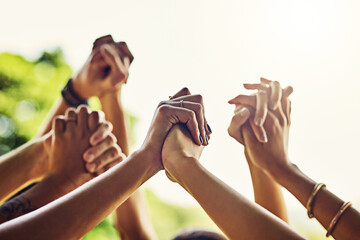 Poster - United together is how well stay. Closeup shot of an unrecognizable group of people holding hands with their arms raised outdoors.