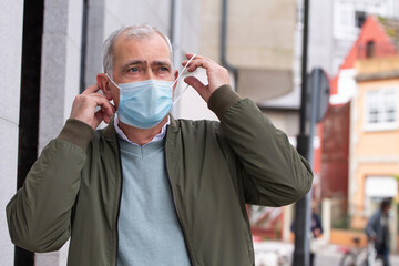 Wall Mural - adult man putting the medical mask on his face