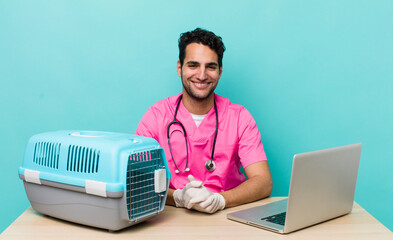 Wall Mural - hispanic handsome man smiling happily with a hand on hip and confident. veterinarian concept