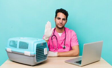 Wall Mural - hispanic handsome man looking serious showing open palm making stop gesture. veterinarian concept