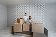 © Andrii - Brother and sister are playing and enjoying moving to a new apartment against the background of cardboard boxes on the couch. Purchase of real estate. Housewarming, delivery.