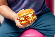 Man holding a spicy fried chicken burger oozing with melted cheese.