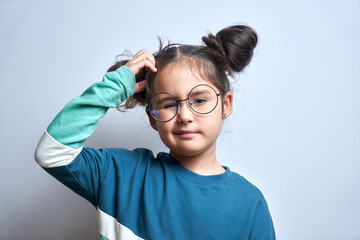 funny little girl in glasses scratching her head doubts, makes decision isolated on yellow studio ba