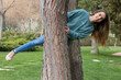 © NOWRA photography - Young woman playing and having fun among the trees while looking at the camera