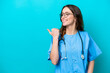 © luismolinero - Young surgeon doctor woman isolated on blue background pointing to the side to present a product