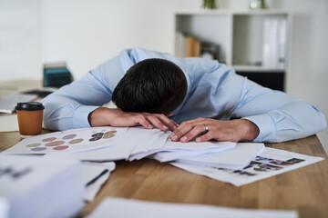 Aufkleber - Its another overwhelming day in the office. Shot of a tired young businessman with his head down on a pile of paperwork in an office.