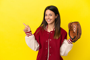 Wall Mural - Young caucasian woman playing baseball isolated on yellow background pointing finger to the side