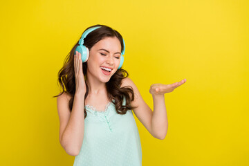 Poster - Photo of charming cute excited female listening cool rap music in headphones isolated on yellow color background