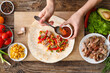 © Pixel-Shot - Woman preparing tasty burrito with meat on wooden background