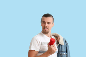 Wall Mural - Young man with modern wireless portable speaker looking aside on blue background