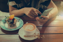 Woman Preparing To Take Pictures Of Piccolo Latte Coffee Cup, Brownies And Breakfast On Wooden Table With Smartphone.