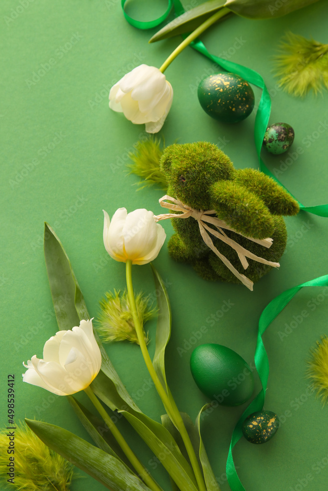 Composition with beautiful Easter eggs, bunny and tulip flowers on green background