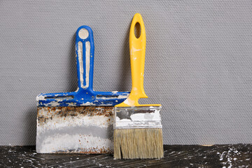 Wall Mural - Spatula for finishing and plastering walls and paint brush gray wall background.