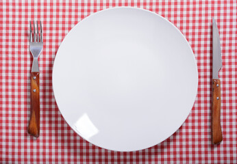 empty plate with fork and knife on red tablecloth