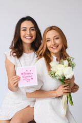 Poster - Young woman and her mother with flowers and greeting card for International Women's Day on light background