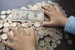 Boy comparing dollar bills and colombian coin pesos, hands with money