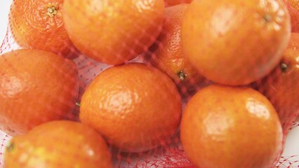 Macro closeup rack focus of honeybell oranges fruit in mesh net bag isolated against white studio background kitchen table