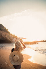 Wall Mural - young woman in a swimsuit with a beautiful figure on the seashore at sunset. Selective focus