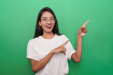 Young Asian Indian Woman Wearing White T-shirt Against Green Background Pointing Finger Right Side Of Herself.