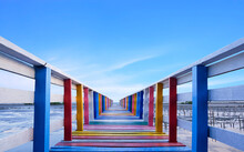 Perspective View Of Vintage Colorful Wooden Bridge Extends Into The Sea Against Blue Sky Background In Evening Time, Rainbow Bridge Is Famous Landmark In Thailand