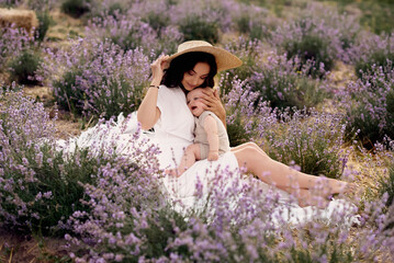 attractive young mother playing with her baby in a lavender field