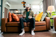 © whyframeshot - relax casual Asian adult Man Wearing Virtual Reality Headset and Holding Controllers Plays in a sport Video Game at Home. Playing VR active sport game online in the Living Room