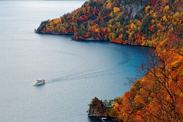 Wall Mural - Aerial view of a sightseeing boat cruising on Lake Towada on a sunny autumn day in Towada Hachimantai National Park, Aomori, Japan. Magnificent scenery of the grand nature in Tohoku, Japan