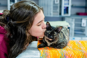 Teen with Dark Hair Kisses and Tortoiseshell Cat in a Shelter