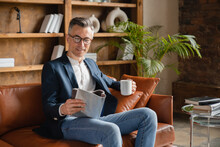 Relaxed Caucasian Mature Middle-aged Businessman Freelancer Ceo Boss Employee Reading Business Journal While Having Breakfast Drinking Coffee At Office Before Working Day