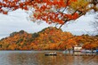 Beautiful scenery of lakeside mountains covered with colorful Japanese maple trees and sightseeing boats on magnificent Lake Towada in autumn season, in Towada Hachimantai National Park, Aomori, Japan