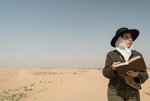 Arabic Female Traveler Writing In Journal In The Desert