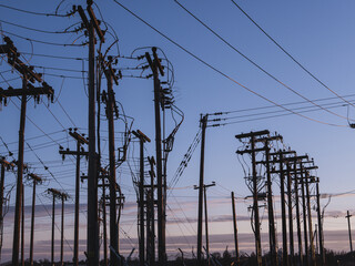 Wall Mural - Old wooden poles with electric wires against a blue cloudy sky