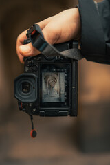 Wall Mural - Shallow focus shot of a man's hand holding a digital camera with the photo of a historical arcade