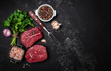 Two fresh raw beef steaks with spices ready to cook on a dark background. Culinary, cooking, concept. banner, menu, recipe place for text, top view