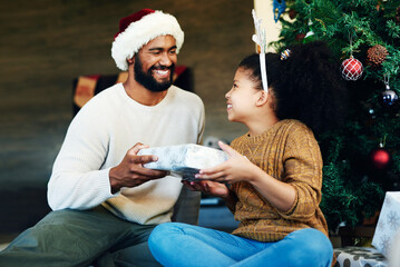 Sticker - Guess what Santa got you. Shot of a cute little girl opening presents with her father during Christmas at home.