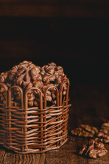 Wall Mural - Walnuts close up in a brown wicker basket on a dark wooden background. Organic food concept.